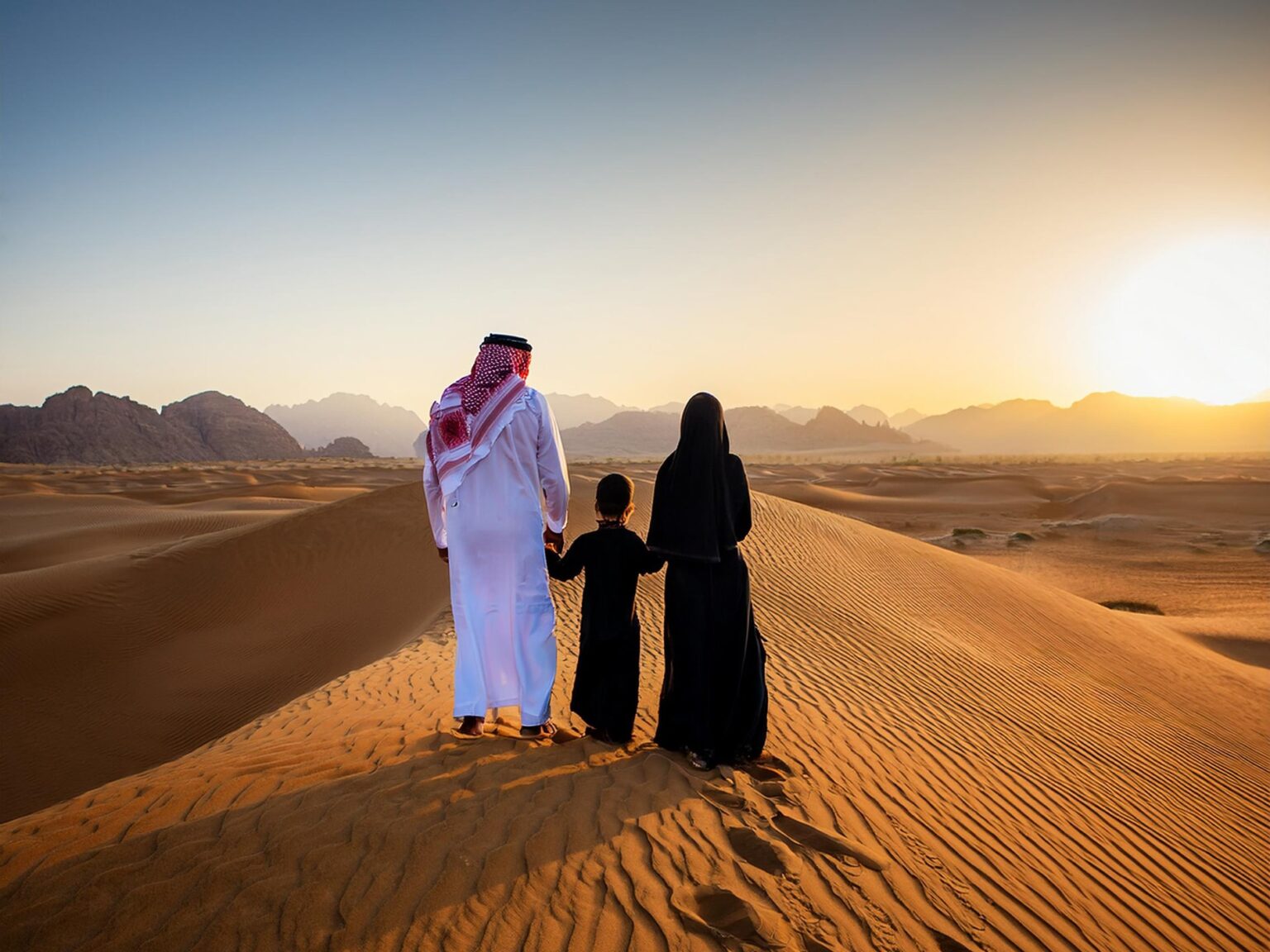 A family enjoying a quiet sunset together on the desert dunes
